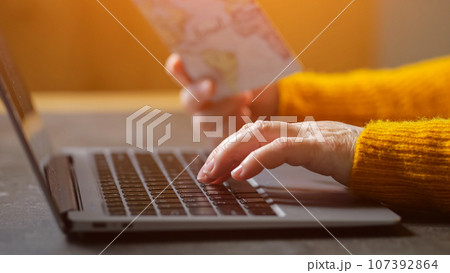 Mature woman hand enters passport data to buy tickets Mature woman hand enters passport data to buy tickets 107392864