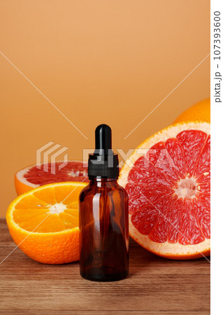 Glass bottle with essential citrus oil on orange background 107393600