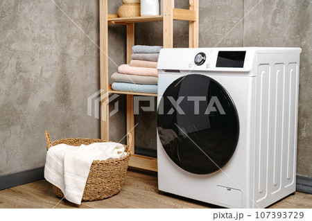 Laundry room interior with washing machine near gray grunge wall Laundry room interior with washing machine near gray grunge wall 107393729