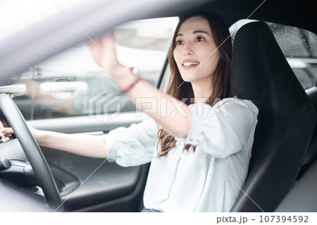 バックミラーをチェックするビジネスカジュアル姿の若い女性 107394592