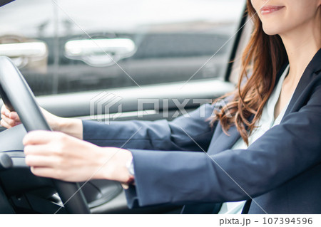 ジャケット姿で運転をするメガネをかけた若い女性　顔無し 107394596