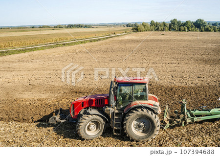 Tractor in the field. Agricultural machinery. Agricultural farm tractor during tillage of soil and field after harvest. 107394688