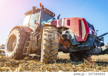Tractor in the field. Agricultural machinery. Agricultural farm tractor during tillage of soil and field after harvest. 107394692