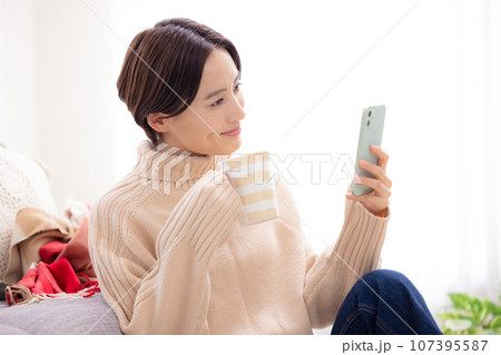 リビングでスマホを見る女性 107395587