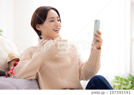 リビングでスマホを見る女性 リビングでスマホを見る女性 107395591