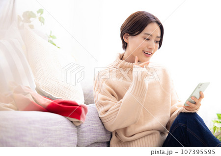 リビングでスマホを見る女性 リビングでスマホを見る女性 107395595
