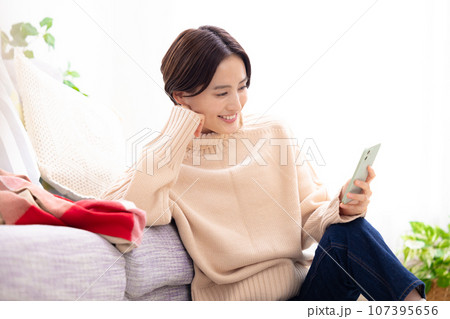 リビングでスマホを見る女性 107395656