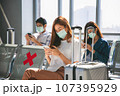 Happy Asian colleagues using smartphone checking flight or online check-in at airport togetherl, summer holiday or mobile phone. 107395929