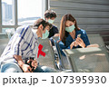 Happy Asian colleagues using smartphone checking flight or online check-in at airport togetherl, summer holiday or mobile phone. 107395930