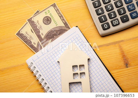 Buy Or Rent concept. Toy house and notepad with calculatoron on wooden background, top view Buy Or Rent concept. Toy house and notepad with calculatoron on wooden background, top view 107396653