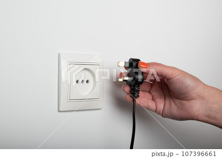 Different standards for electrical outlets. Unsuitable connector and plug in the hand of a person. Incompatibility, concept Different standards for electrical outlets. Unsuitable connector and plug in the hand of a person. Incompatibility, concept 107396661
