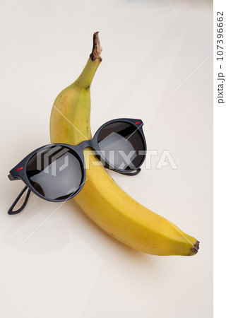 A funny banana with black sunglasses on a white background. A funny banana with black sunglasses on a white background. 107396662