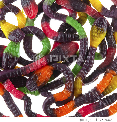 Texture of randomly scattered gelatin candies made in the form of colorful snakes. Gelatin cobras. Texture of randomly scattered gelatin candies made in the form of colorful snakes. Gelatin cobras. 107396671