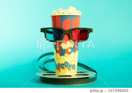 Movie clapper, pop corn, 3D glasses and film reel on blue background. Collage design 107396805