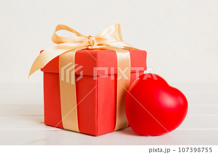 gift box with red bow and red heart on colored background. Perspective view. Flat lay 107398755