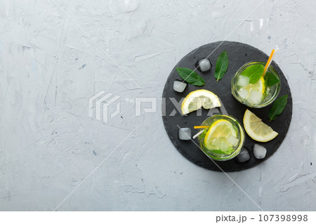 Caipirinha, Mojito cocktail, vodka or soda drink with lime, mint and straw on table background. Refreshing beverage with mint and lime in glass top view flat lay 107398998
