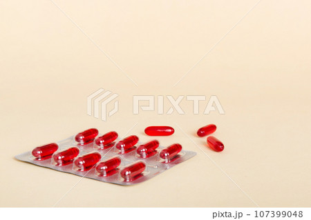 Blister package with Vitamin a on color background. Medicine pills on a light background. Medicines and prescription pills flat lay background. red medical tablets in blister 107399048