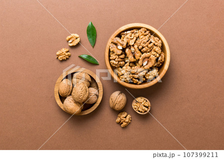 Walnut kernel halves, in a wooden bowl. Close-up, from above on colored background. Healthy eating Walnut concept. Super foods with copy space 107399211