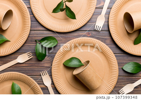 set of empty reusable disposable eco-friendly plates, cups, utensils on light white colored table background. top view. Biodegradable craft dishes. Recycling concept. Close-up set of empty reusable disposable eco-friendly plates, cups, utensils on light white colored table background. top view. Biodegradable craft dishes. Recycling concept. Close-up 107399348