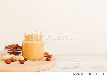 Bowl of peanut butter and peanuts on table background. top view with copy space. Creamy peanut pasta in small bowl 107399351