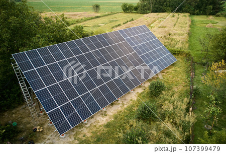 Aerial view of solar panels in green field at daytime. Different types of ground-mounted photovoltaic systems. Concept of ecological energy. Photo-voltaic collection of modules as a PV panel. Aerial view of solar panels in green field at daytime. Different types of ground-mounted photovoltaic systems. Concept of ecological energy. Photo-voltaic collection of modules as a PV panel. 107399479