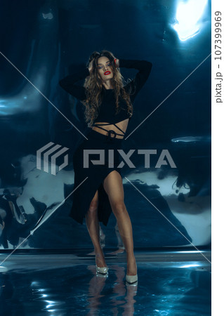 Sexy fashionable lady in black dress posing in studio on dark foil background 107399969