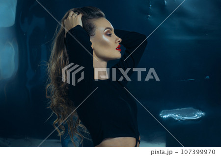 Sexy fashionable lady in black dress posing in studio on dark foil background 107399970