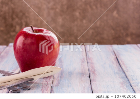 Close up red apple and toy airplane on wooden background. 107402050