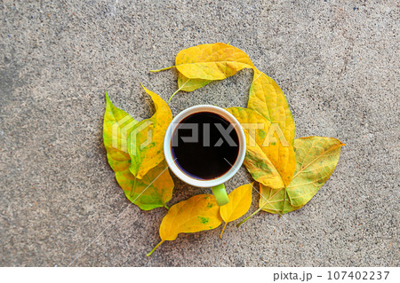 cup of coffee with autumn leaves on cement floor 107402237
