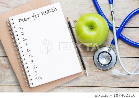 Top view green apple with blue stethoscope on wood table background. 107402316