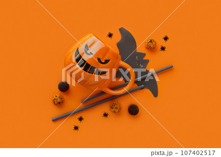 Pumpkin cup, gummy, straws, bat napkin on orange background. Halloween celebration concept 107402517