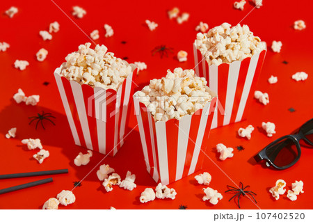 Striped boxes with popcorn on a red background Striped boxes with popcorn on a red background 107402520