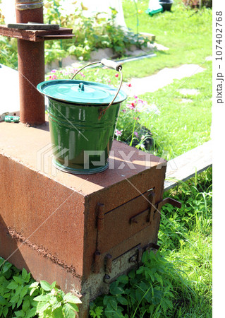 A metal bucket stands on a homemade cast-iron stove in the vegetable garden 107402768