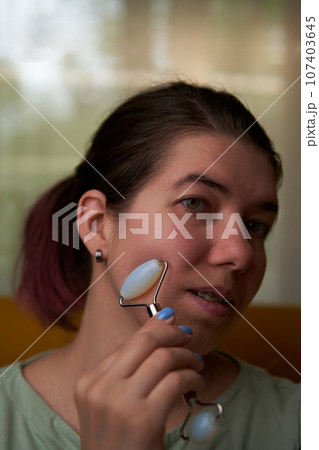 Woman is massaging her face roller. 107403645