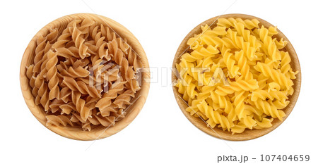 Wolegrain fusilli pasta from durum wheat in wooden bowl isolated on white background with full depth of field. Top view. Flat lay. Wolegrain fusilli pasta from durum wheat in wooden bowl isolated on white background with full depth of field. Top view. Flat lay. 107404659