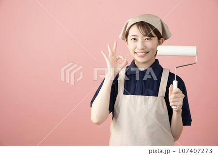 ピンクバックでコロコロを持つハウスクリーニングの女性作業員 107407273