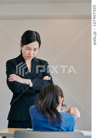 腕組みをして女の子を叱る女性の教師 腕組みをして女の子を叱る女性の教師 107407405