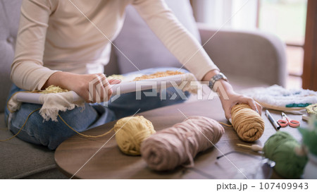 Asian woman putting yarn on table after embroidery on fabric with punch needle in hobby lifestyle 107409943