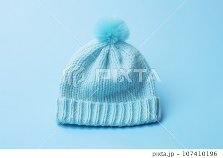 Baby boy knitted warm wool hat cap with pompon on blue background. Generative AI Baby boy knitted warm wool hat cap with pompon on blue background. Generative AI 107410196