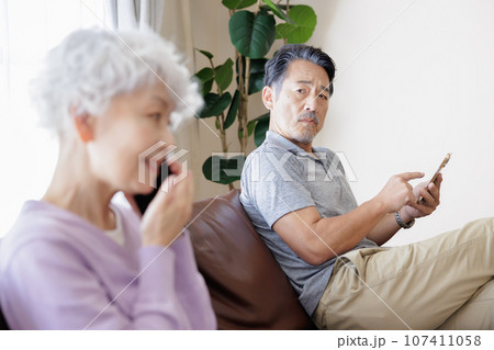 スマートフォンで会話をするシニア女性と男性 スマートフォンで会話をするシニア女性と男性 107411058