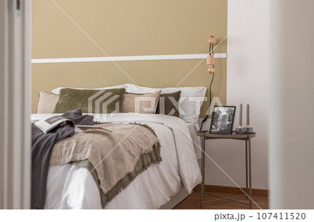 Side shot of edge of large cozy double bed with a bedside table in beige color in a hotel room. The concept of comfortable living in a business hotel with a convenient location and five-star service 107411520