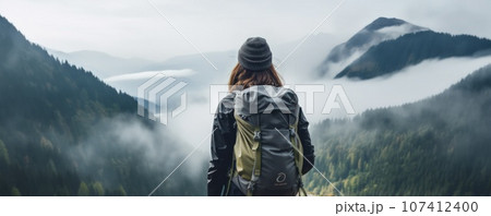 A young couple of hikers walk through the forest in rainy weather. 107412400