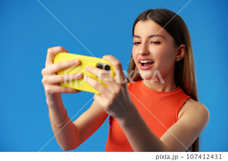 Stylish teen girl using smartphone over blue background 107412431