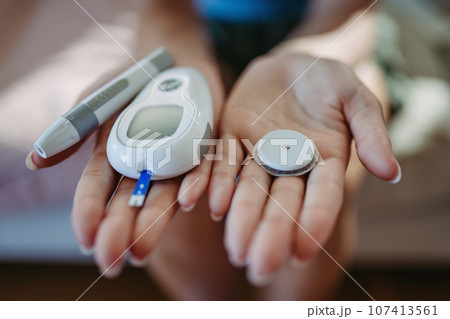 Close up of hands with diabetes supplies and devices. Close up of hands with diabetes supplies and devices. 107413561