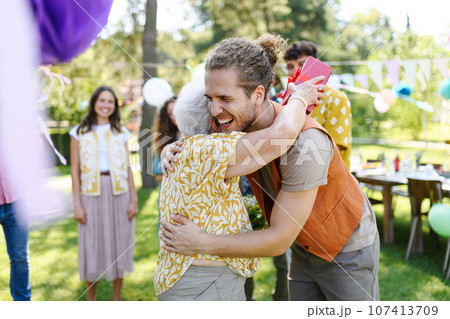 Beautiful senior birthday woman receiving gift from grandson. 107413709