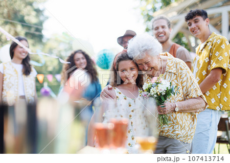 Beautiful senior birthday woman receiving flowers from granddaughter. 107413714