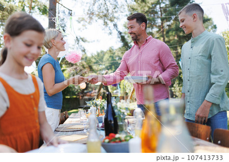 Family setting table for summer garden party. Family setting table for summer garden party. 107413733