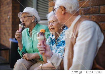 Portrait of three senior friends in the city, eating ice cream on a hot summer day. 107413915