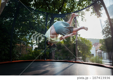Little girl jumping on trampoline on backyard. 107413936