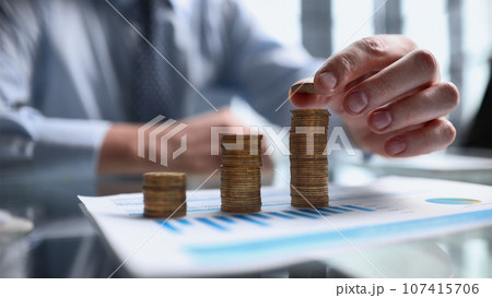 Businessman stacking coins on table, business growth concept. Hand puts coin to stack. 107415706